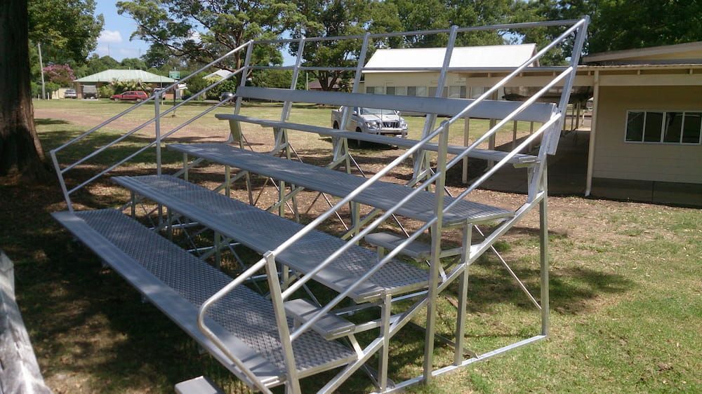 A Metal Bleacher is Sitting in the Grass in Front of a House— Riverside Aluminium & Stainless in Coolongolook, NSW