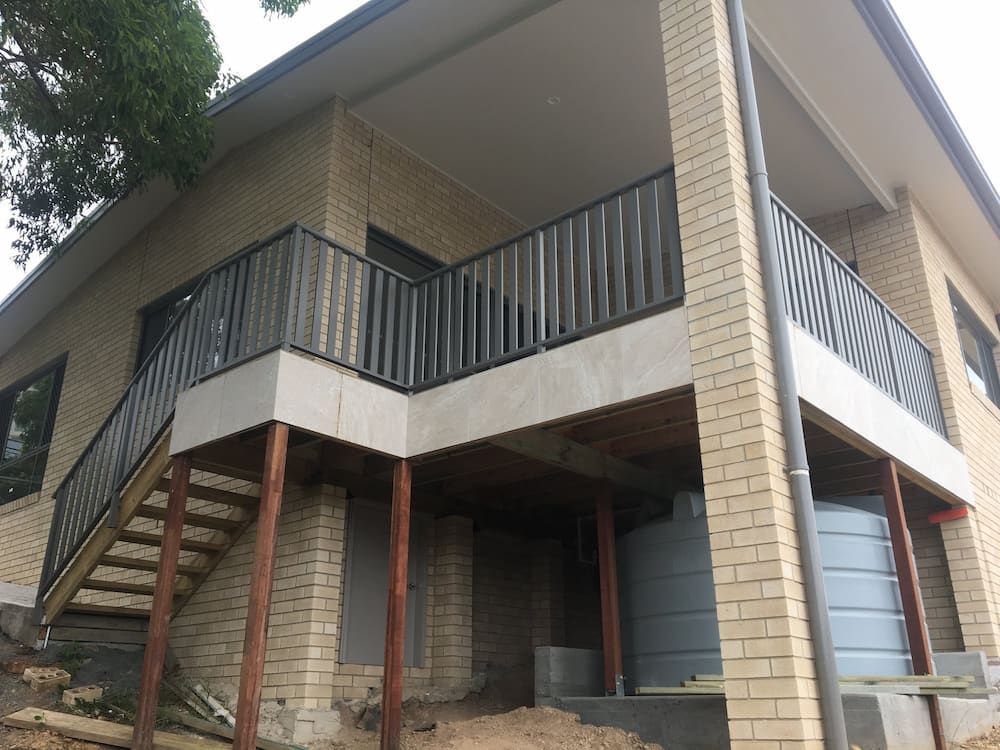 A Brick House With a Balcony and Stairs — Riverside Aluminium & Stainless in Coolongolook, NSW