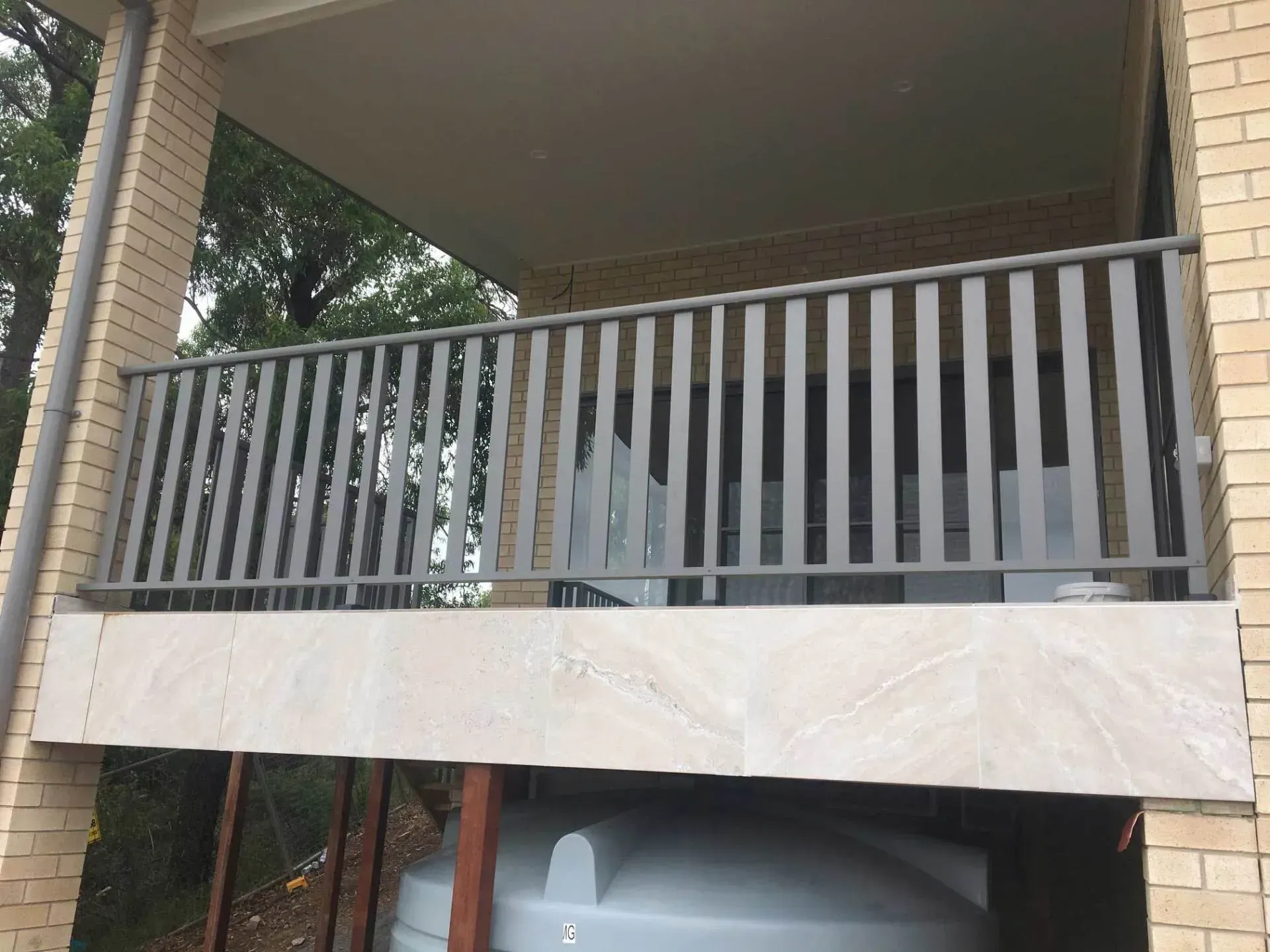A balcony with a metal railing on a brick building — Riverside Aluminium & Stainless in Forster, NSW