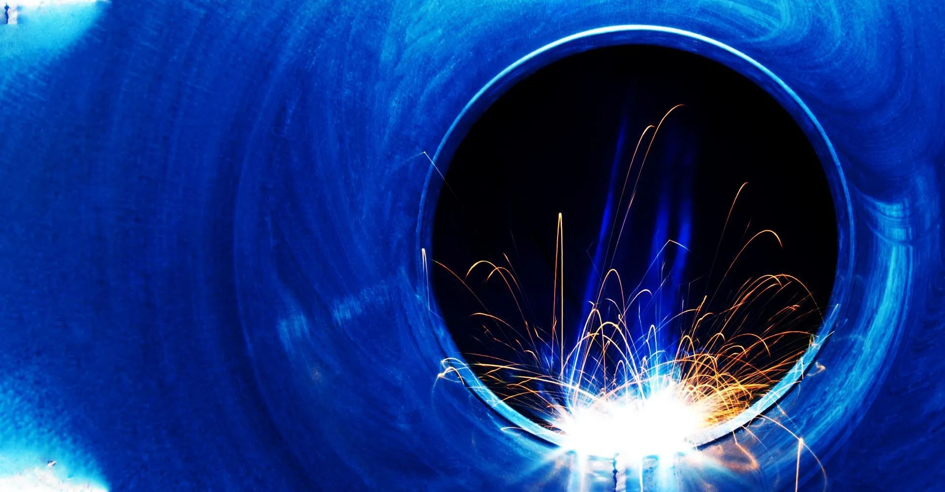 A person is welding a metal pipe in a dark room — Riverside Aluminium & Stainless in Coolongolook, NSW