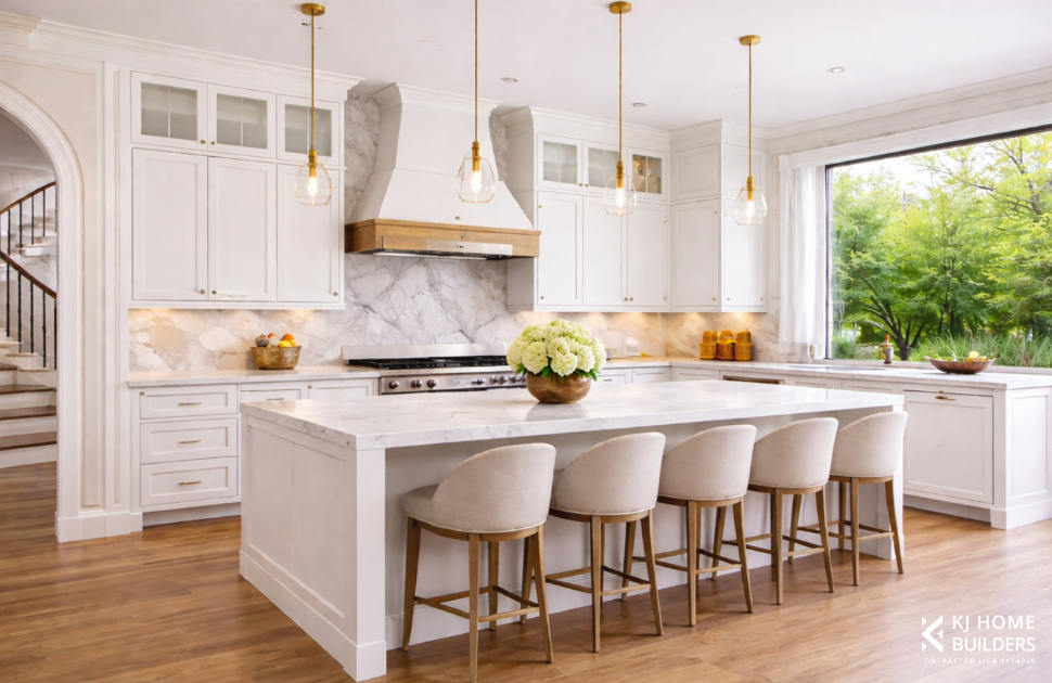 Bright white kitchen with island, bar stools, marble backsplash, gold pendant lights, and a large window