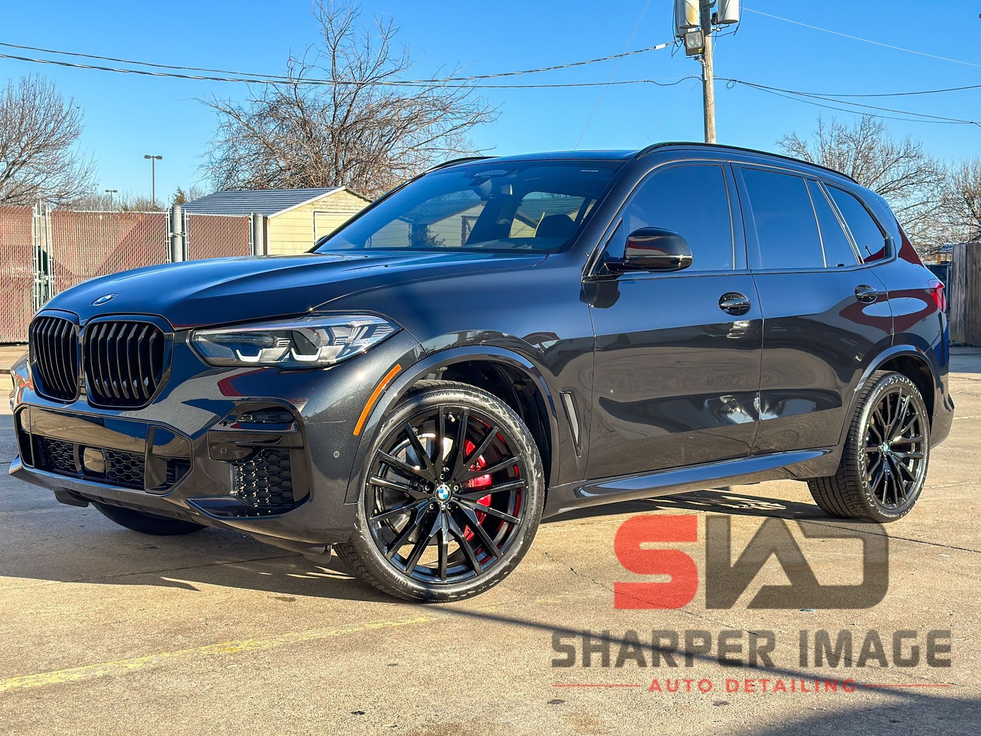 Dark gray BMW SUV with black wheels and red brake calipers, parked outdoors.