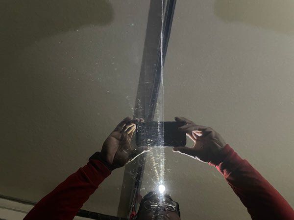 Reflection of a person holding a phone, photographing a ceiling. Red sleeves are visible.
