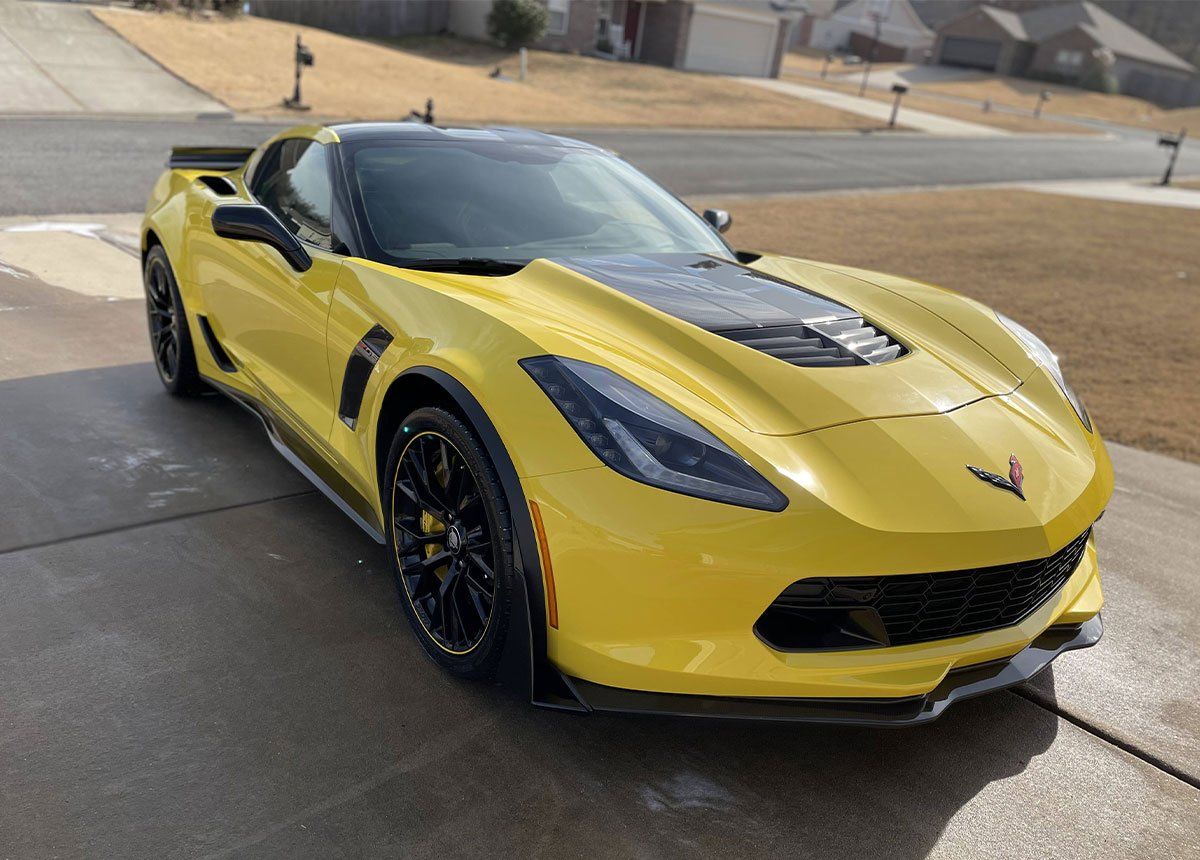 Yellow Chevrolet Corvette sports car parked on a driveway.