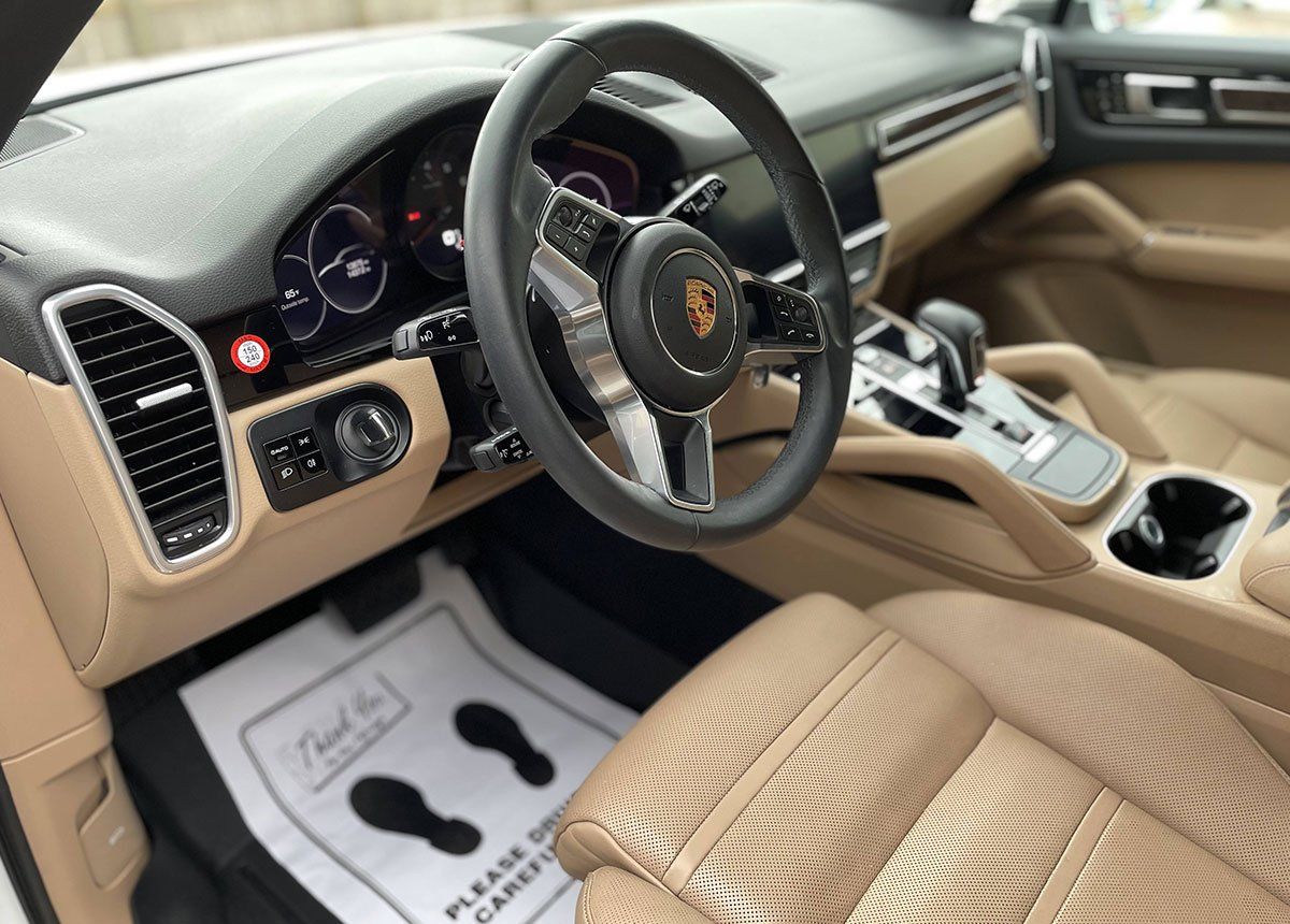 Interior of a Porsche Cayenne with tan leather seats and steering wheel, 