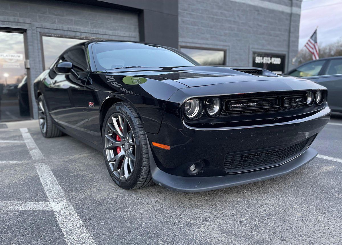 Black Dodge Challenger parked in front of a building.