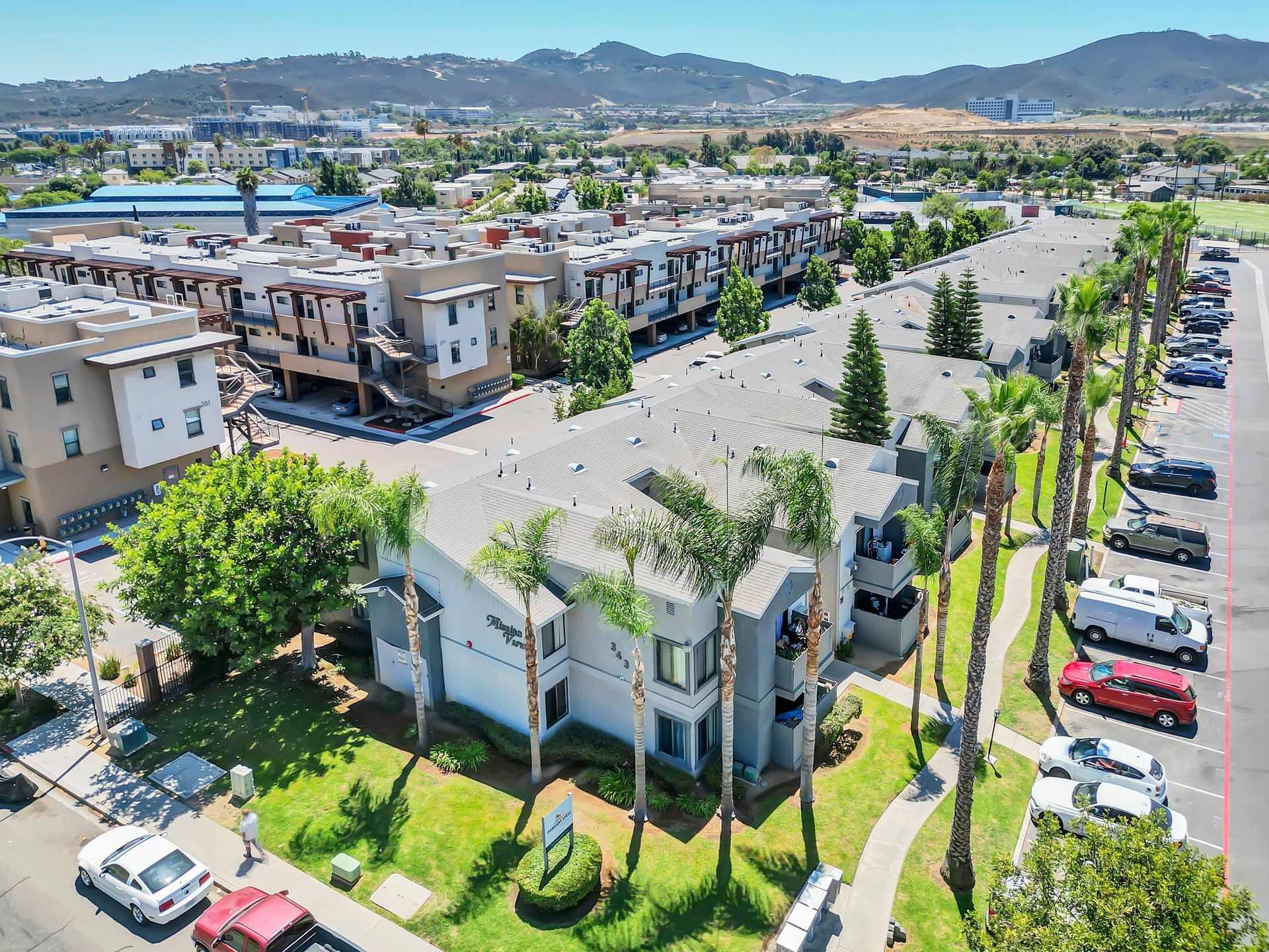 An aerial view of a apartment complex with cars parked in front of it.