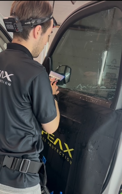 Man in black shirt installing tint on a car window