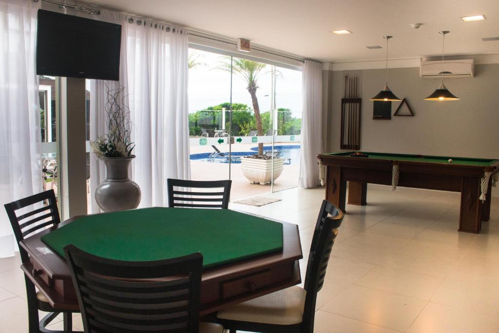 Sala de jogos com mesa de sinuca, mesa de pôquer e vista para a área da piscina.