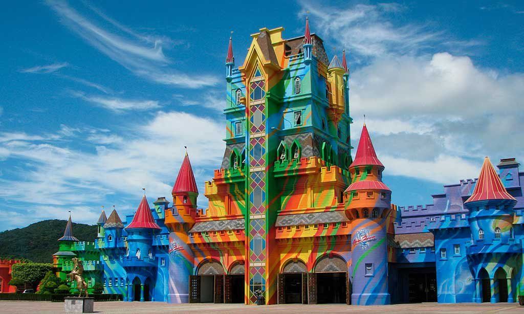 Fachada colorida do castelo com várias torres contra um céu azul.