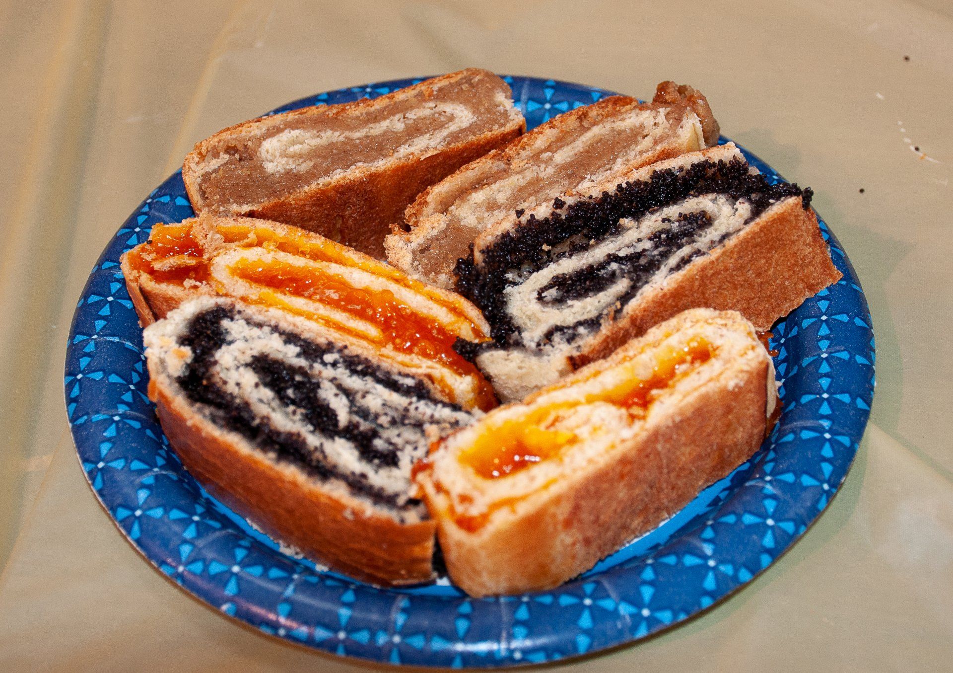 Blue plate with assorted sliced Swiss roll cakes, including chocolate and orange fillings