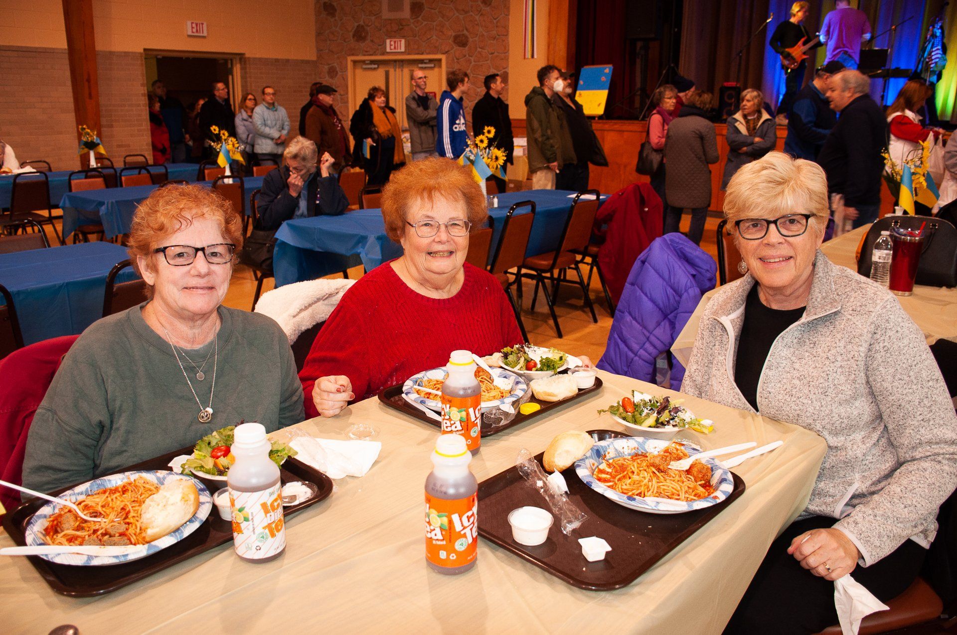 Three people seated at a banquet table with plated meals and drinks in a banquet hall
