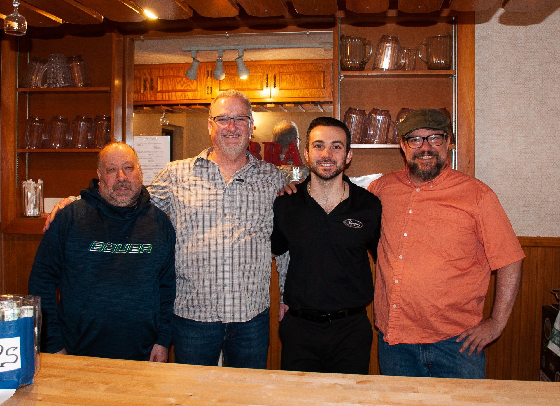 Four people standing together in a warmly lit kitchen, smiling at the camera.