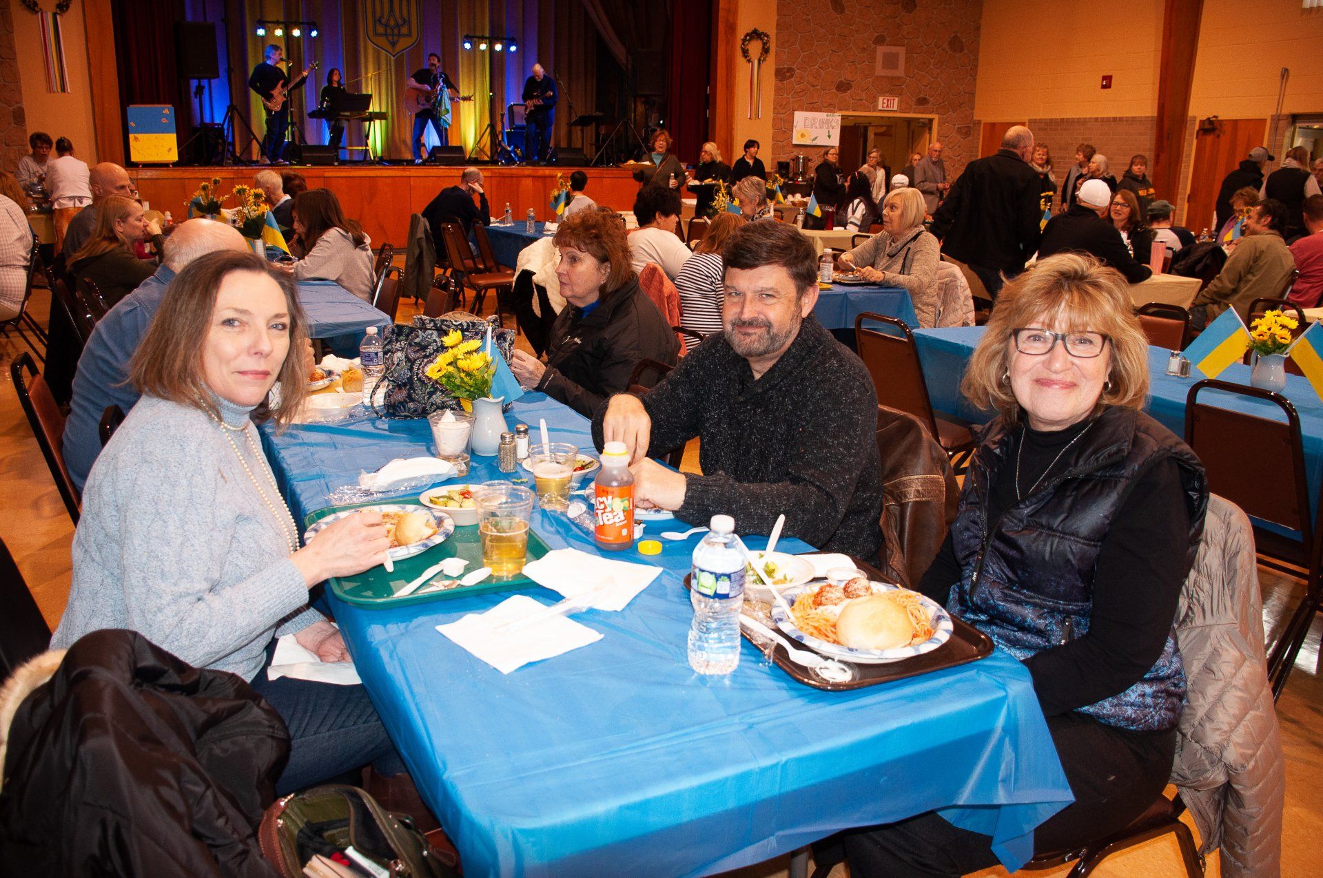 People seated at a banquet table with blue tablecloths in a decorated event hall