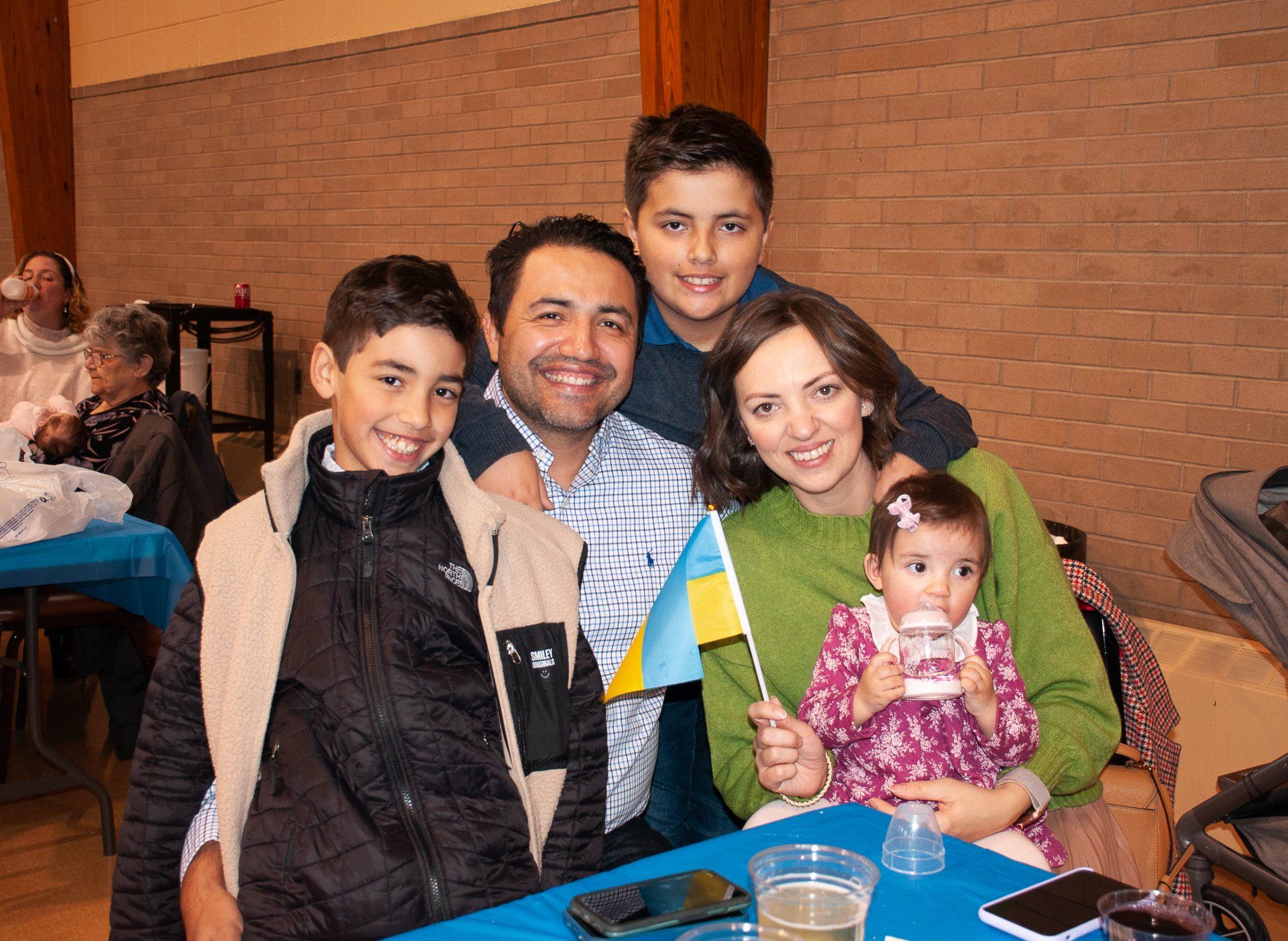 Family posing at a table indoors, with small flags and a baby in a pink outfit.