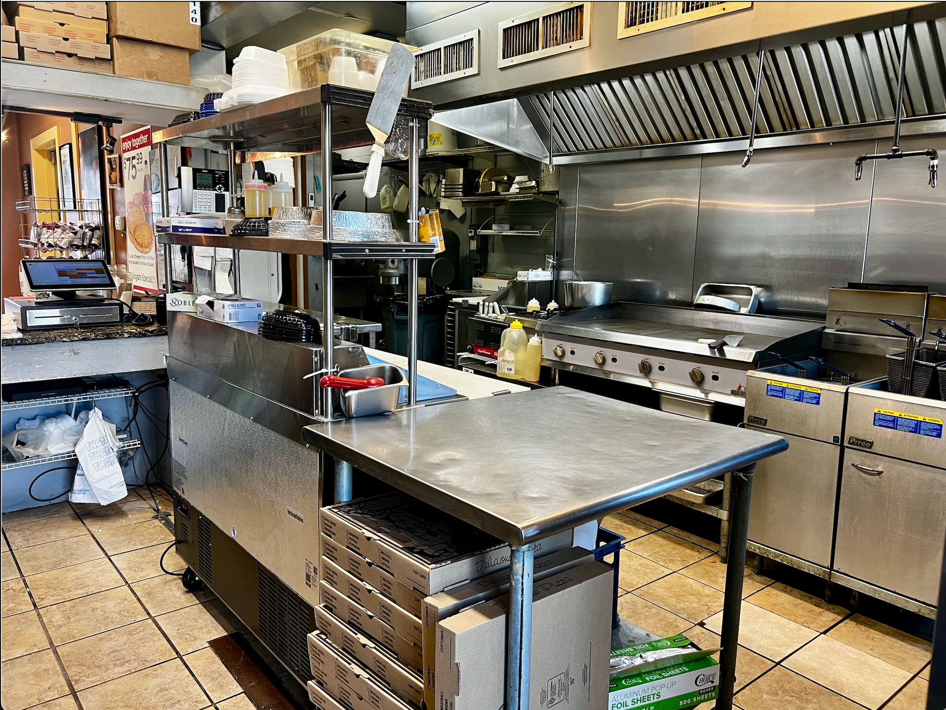 Commercial kitchen with stainless steel prep tables, appliances, and a tiled floor