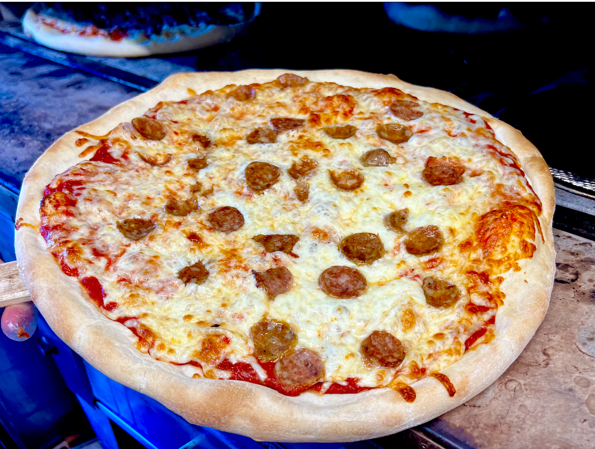 Pepperoni pizza with melted cheese on a round pan, viewed close-up against a dark background