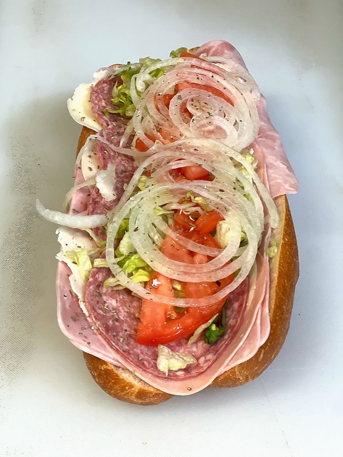 Open-faced sandwich topped with sliced meat, tomato, onion rings, and spread on bread