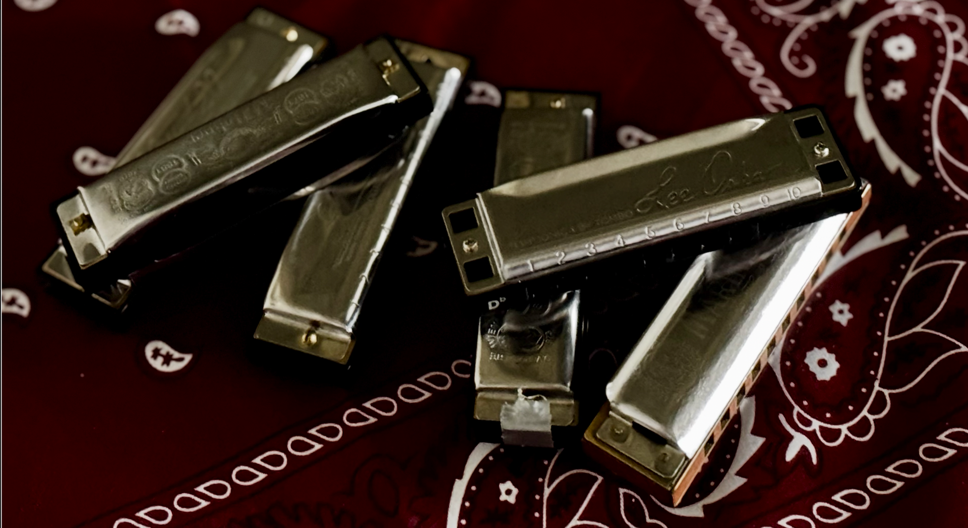 Four silver metal nail clippers on a dark red patterned cloth