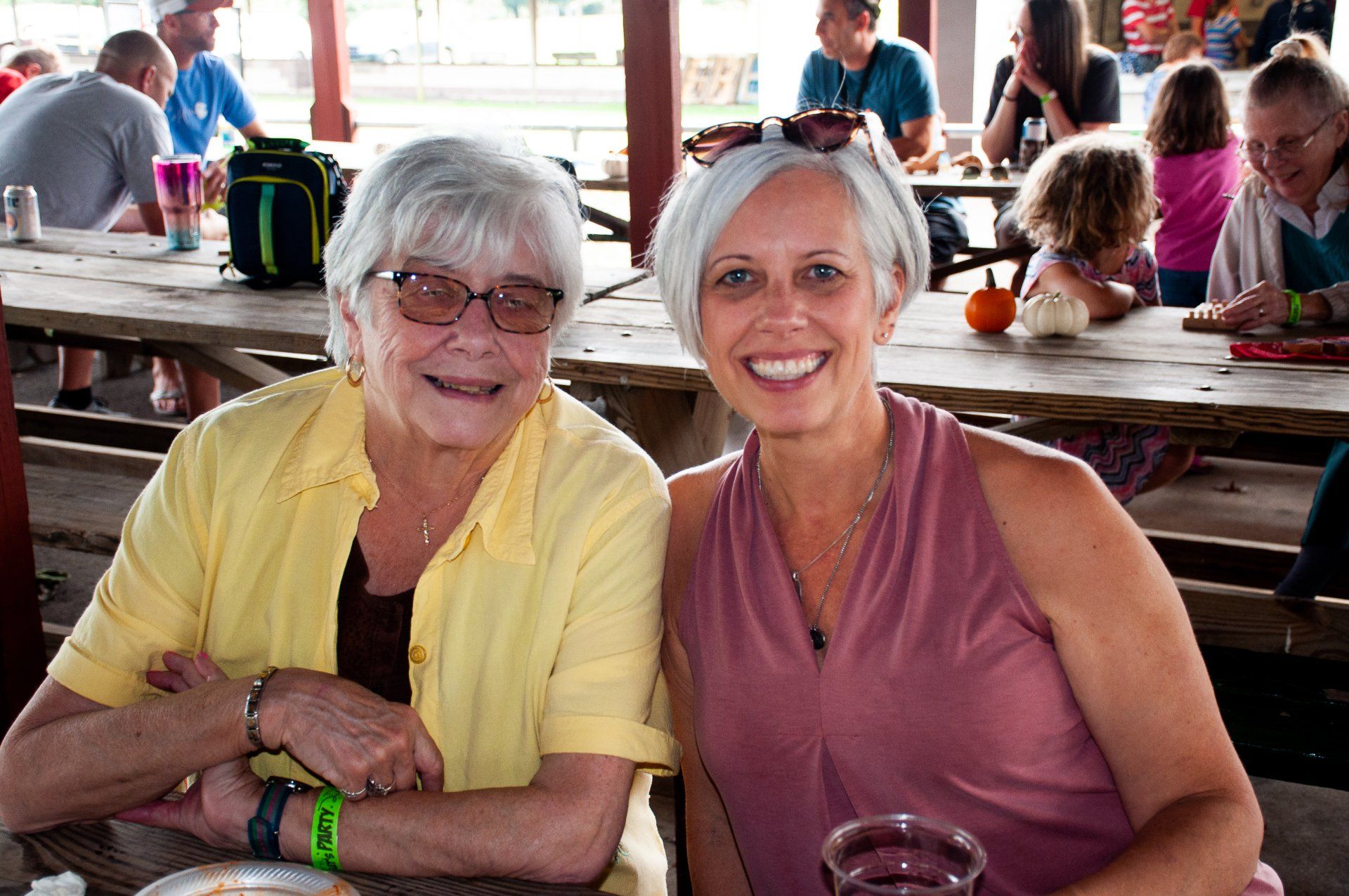 Two women smiling at a picnic table in a casual outdoor dining area