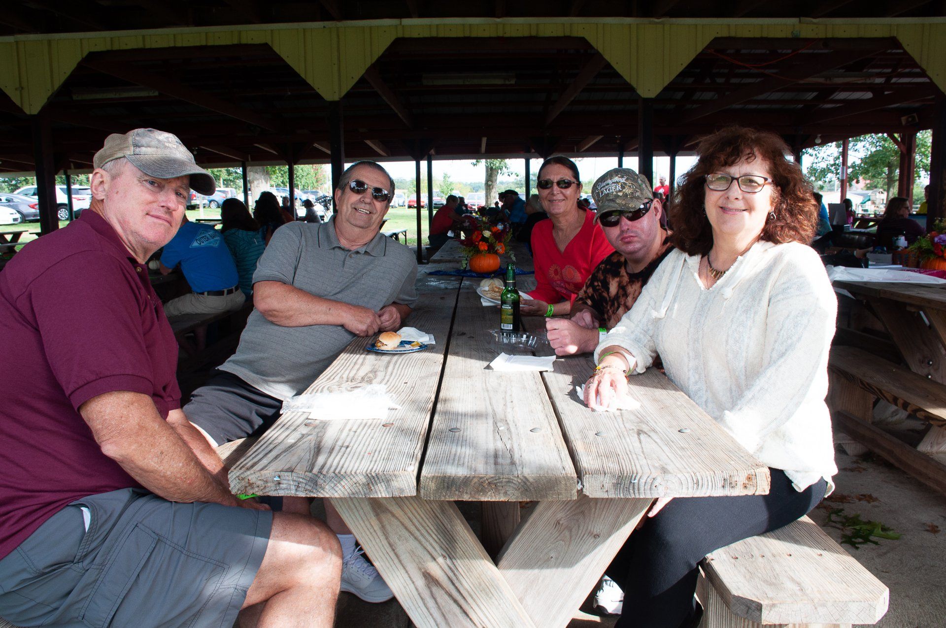Four people sitting and chatting at a picnic table in an open-air pavilion