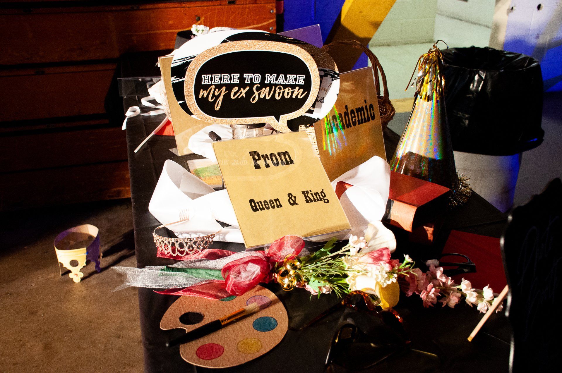 Art supplies and a gift display on a table with flowers and a sign reading “Prom” and “Keep a Cool”