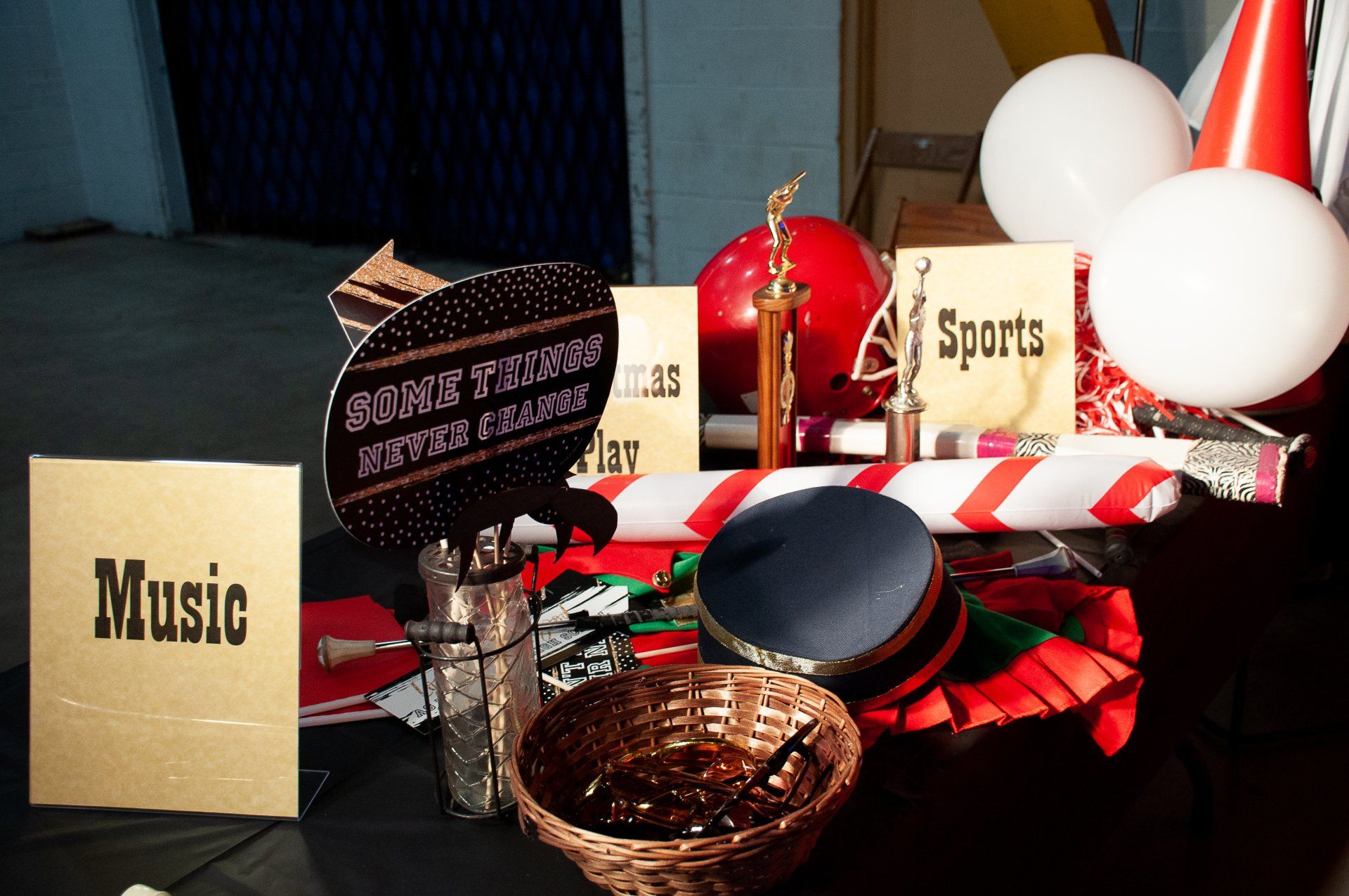 Assorted party decorations, balloons, and signs on a table, including a “Music” sign and red-white accents