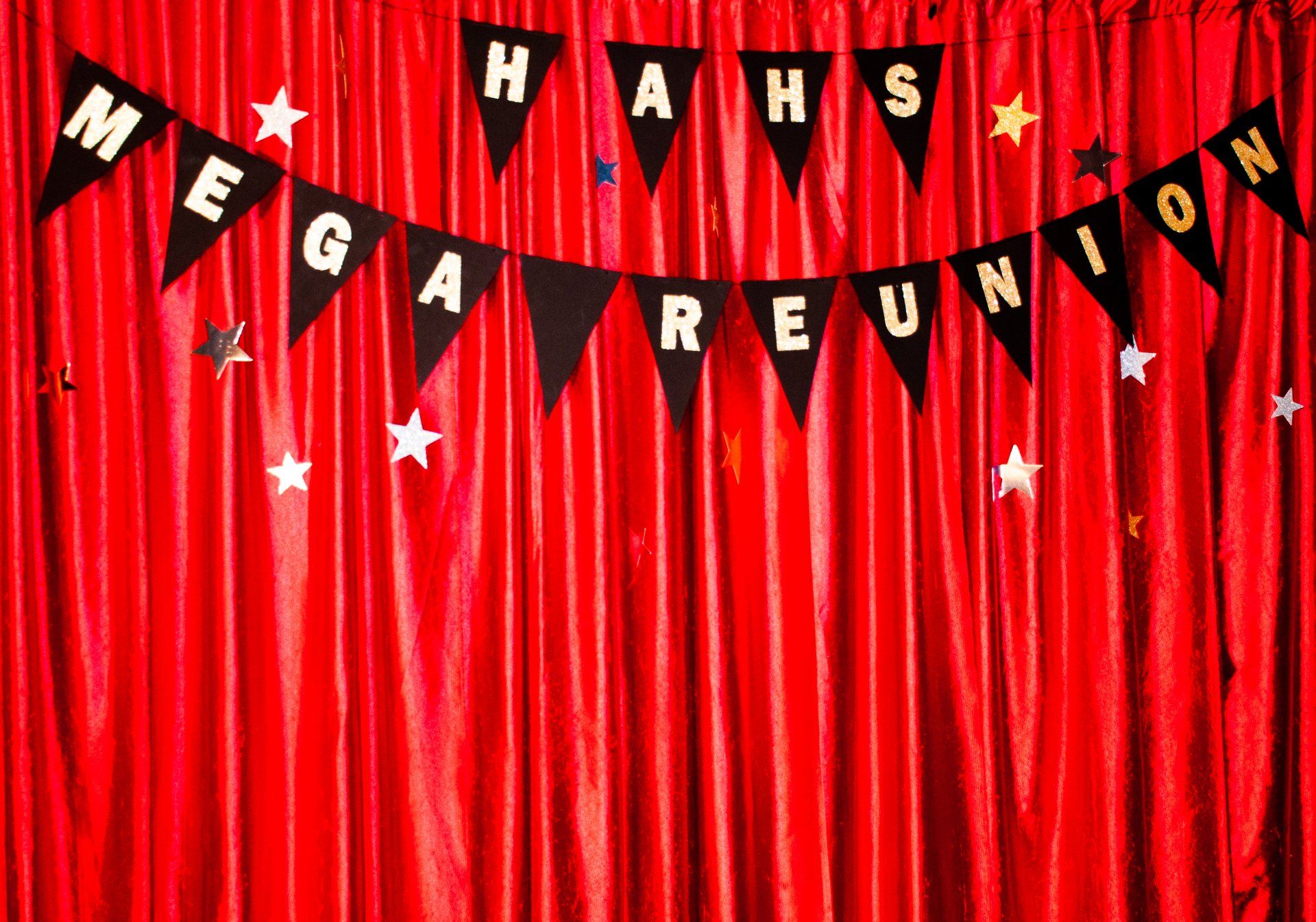 Red curtain backdrop with black pennant banners spelling “Hahas Mega Reunion” and scattered stars