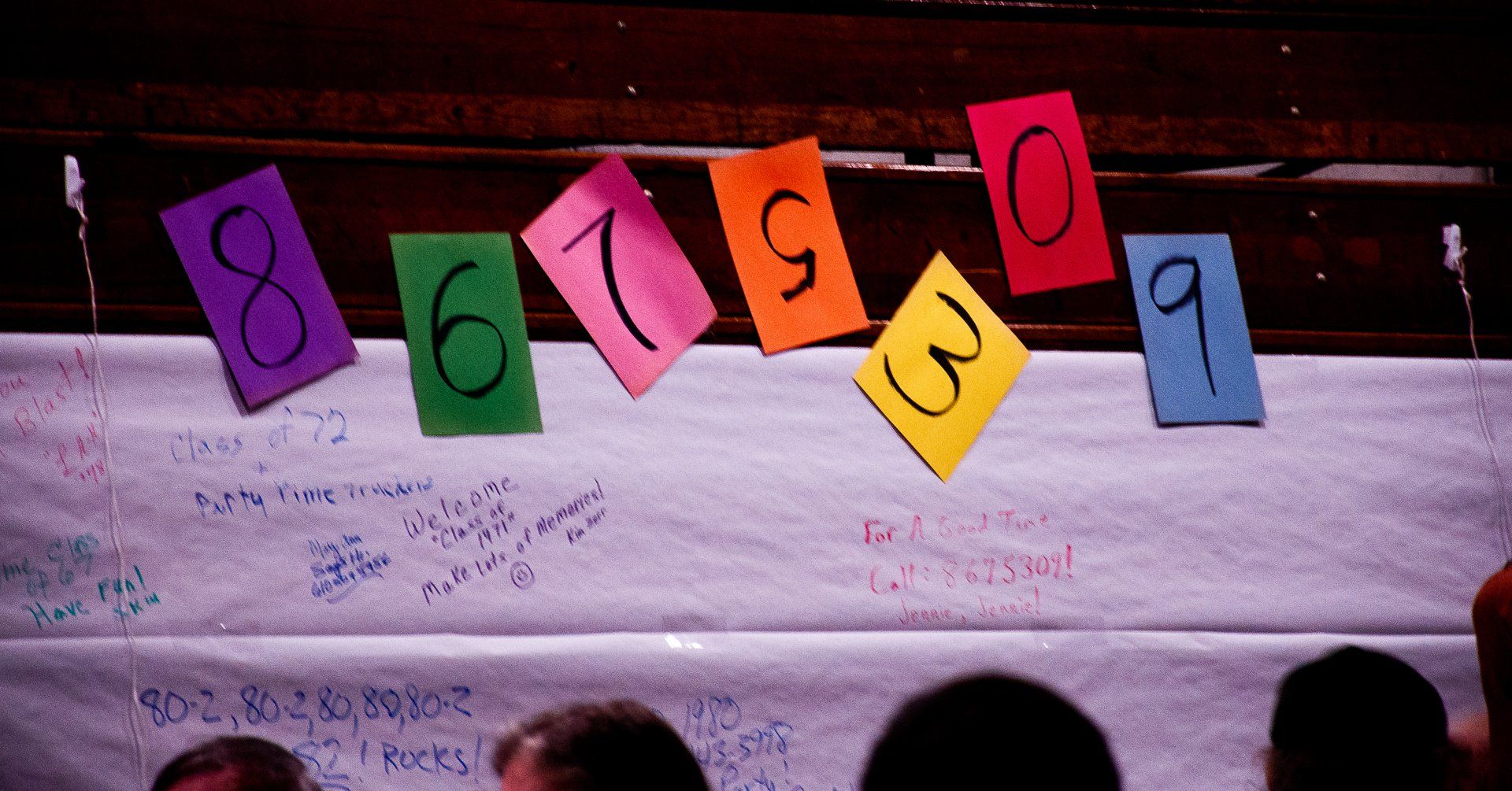Colorful numbered cards hang on a stage backdrop above a crowd silhouette.