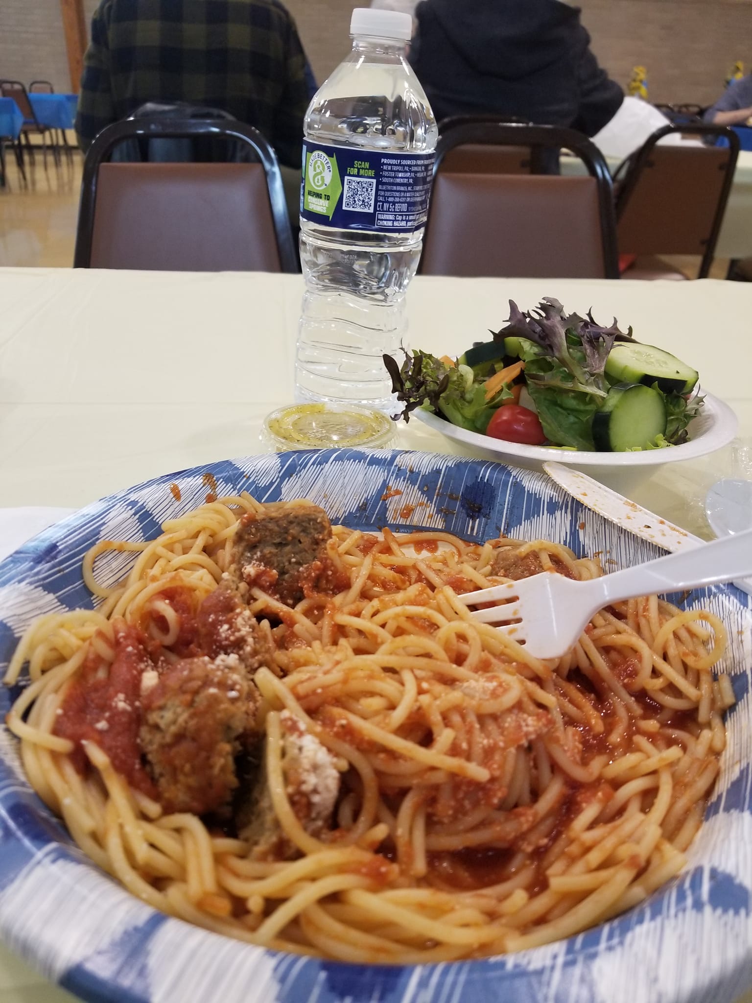 Plate of spaghetti with meat sauce and salad on a table in a casual restaurant.