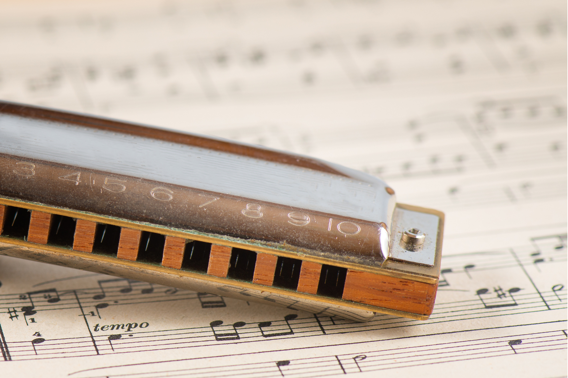 Harmonica resting on sheet music, with a warm wood and metal body.