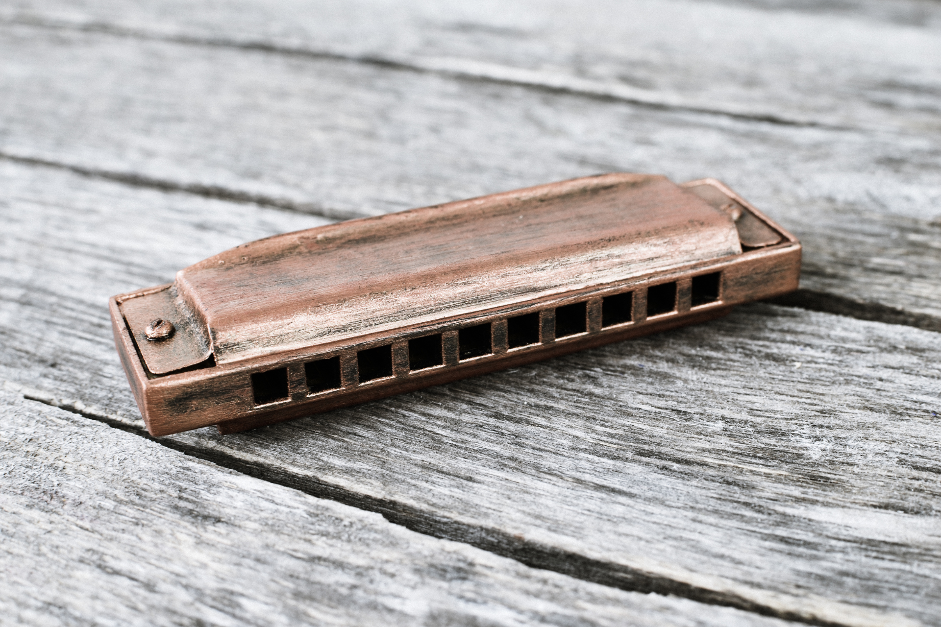 Close-up of a rusty harmonica lying on a weathered wooden surface