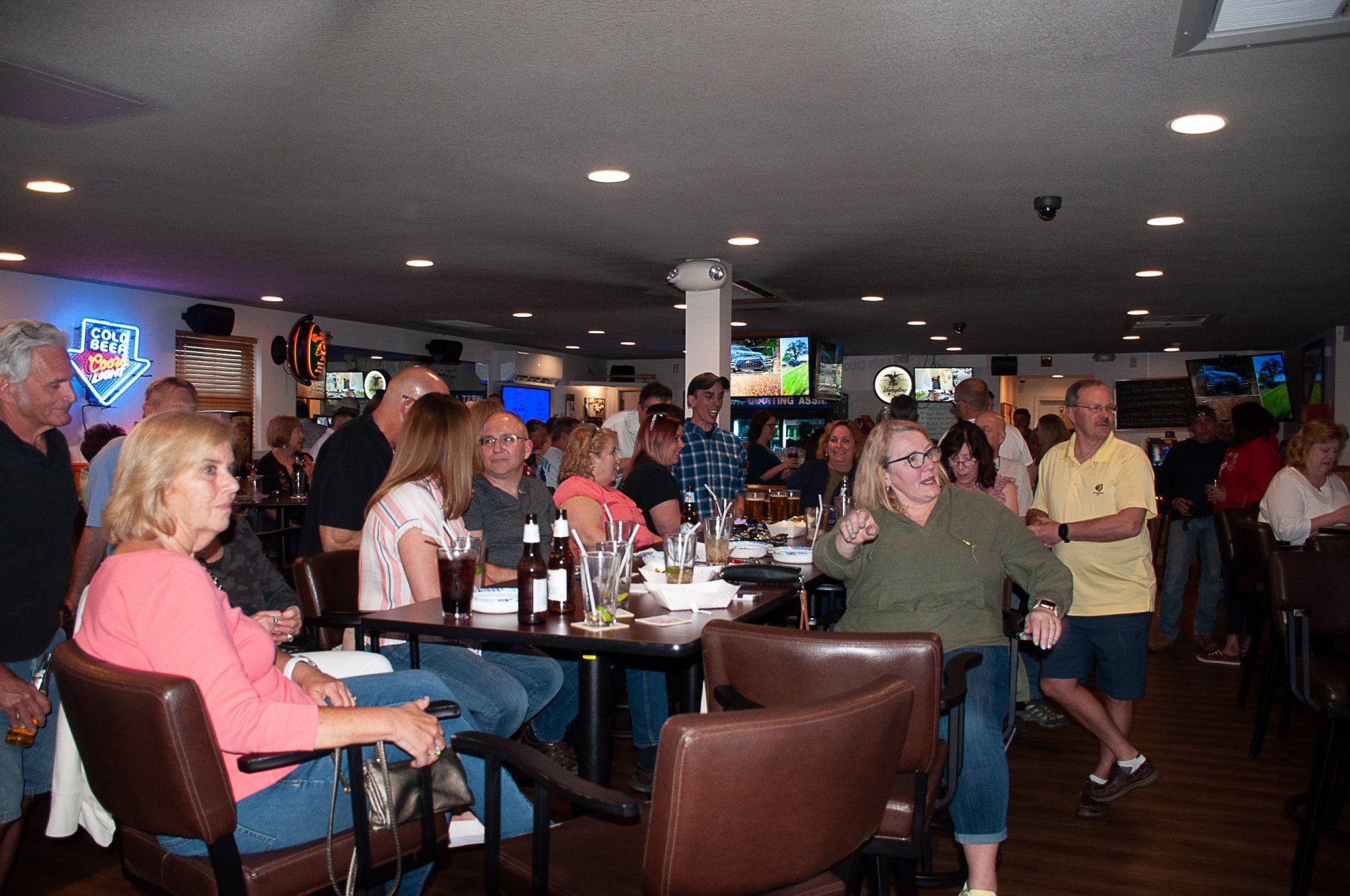 People seated at tables in a busy bar or lounge, chatting under dim lights