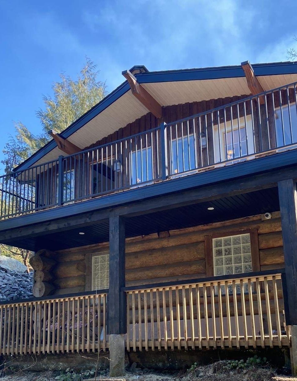 Log cabin with a blue roof and wooden porches under a clear sky