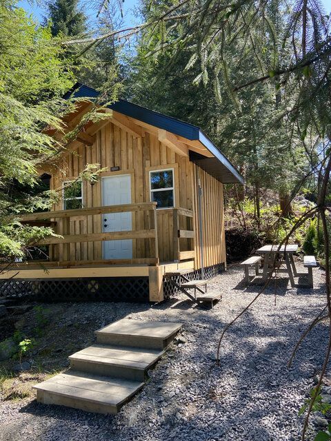 Wooden cabin with porch and steps in a sunny wooded campsite