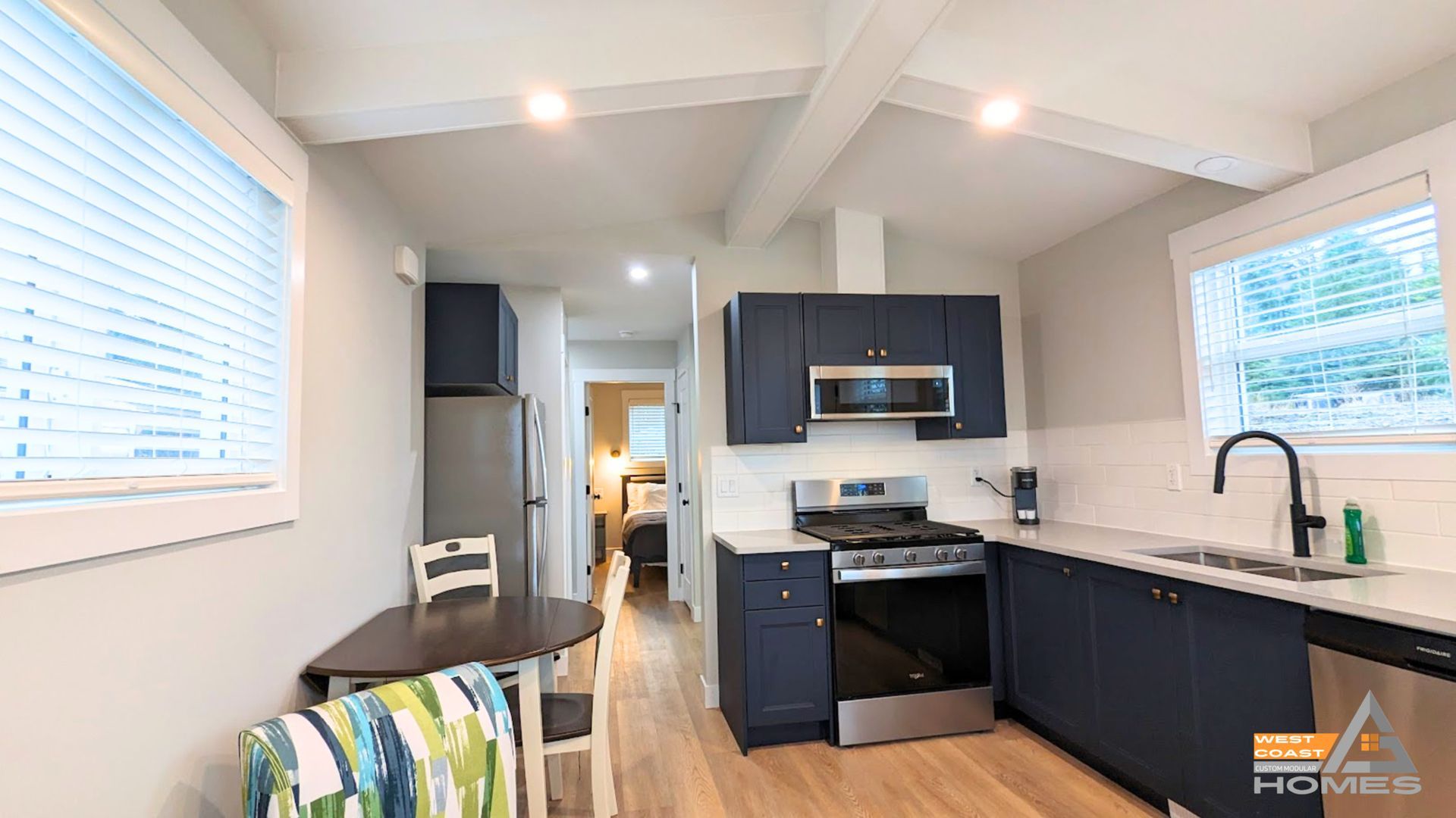 Modern kitchen and dining nook with dark cabinets, stainless stove, and light gray walls.