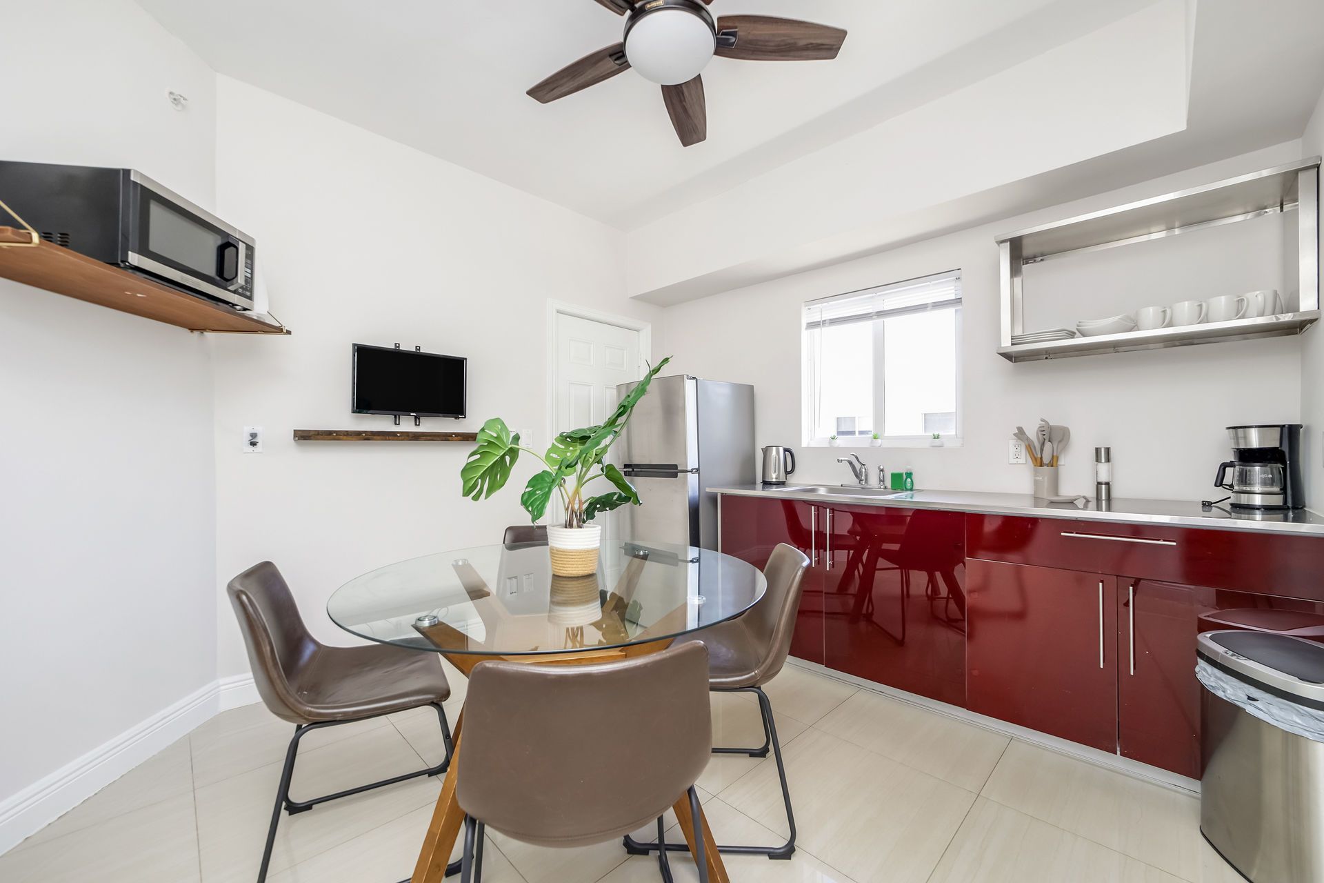 Kitchen with red cabinets, dining table, and appliances like a microwave and refrigerator.