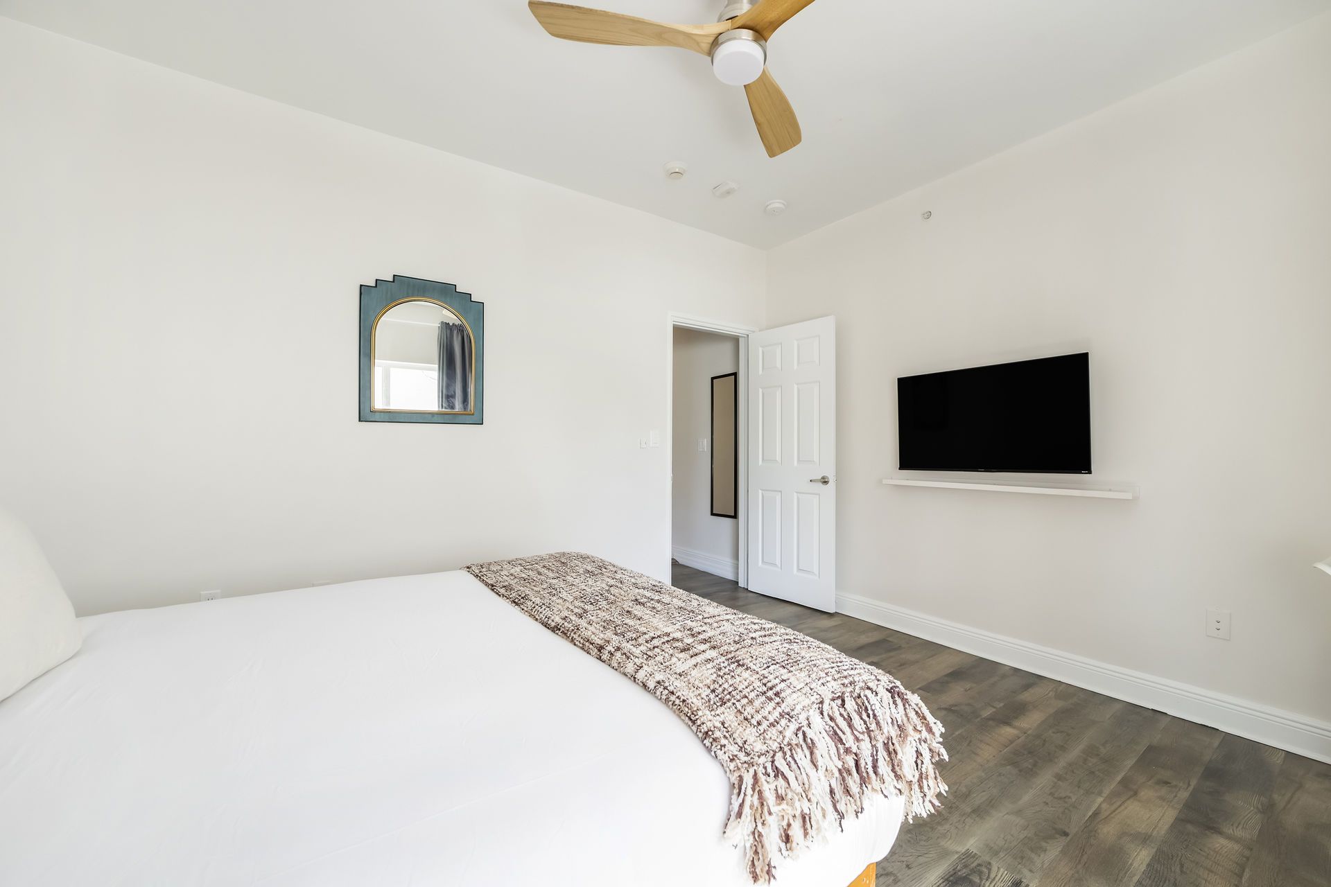 Bedroom with bed, TV, ceiling fan, and doorway.