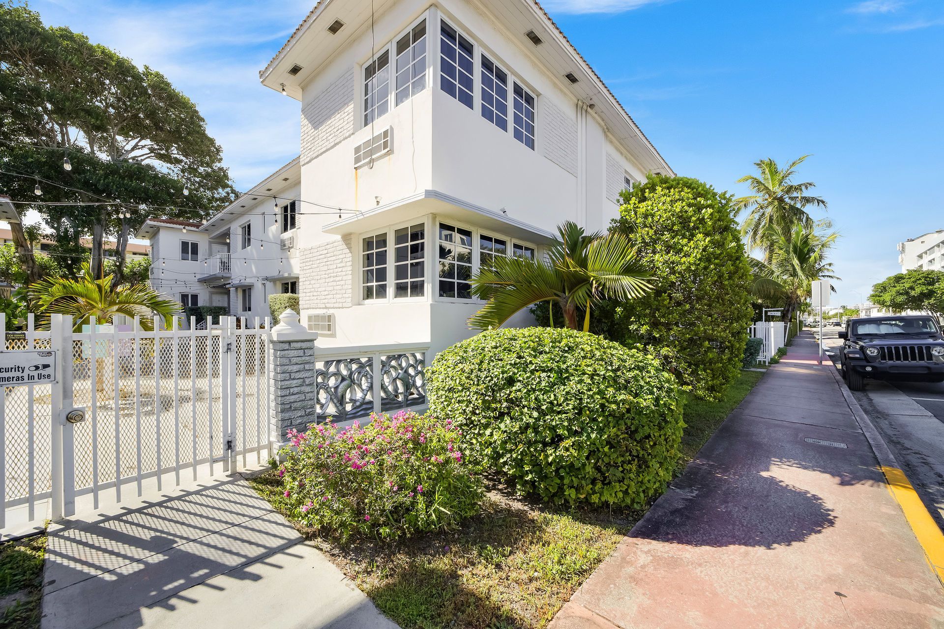White Art Deco building with palm trees and a gate.