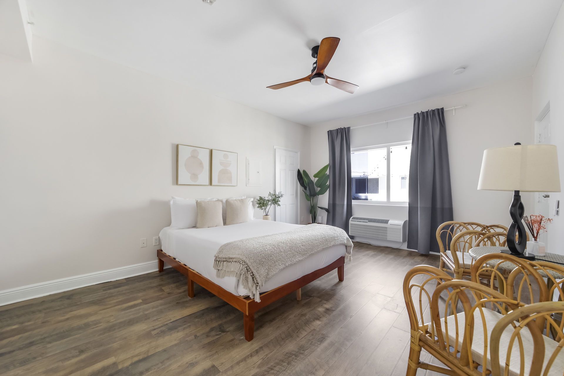 Bedroom with bed, rattan chairs, a lamp, and a ceiling fan.