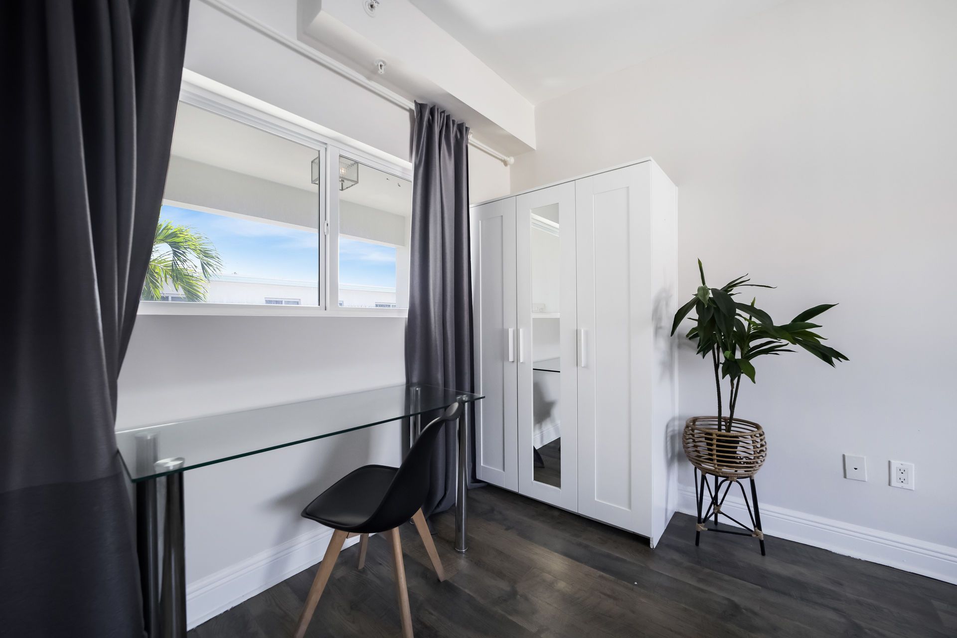 Interior with a window, desk, chair, white wardrobe, and a plant in a patterned pot.