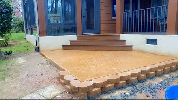 Outdoor patio with stacked brick border, steps leading to a door, and a partially enclosed porch.