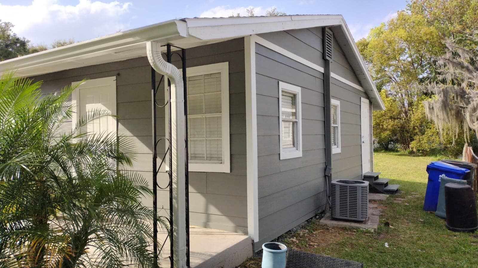 Gray house with white trim, gutters, and windows; air conditioner on the side.