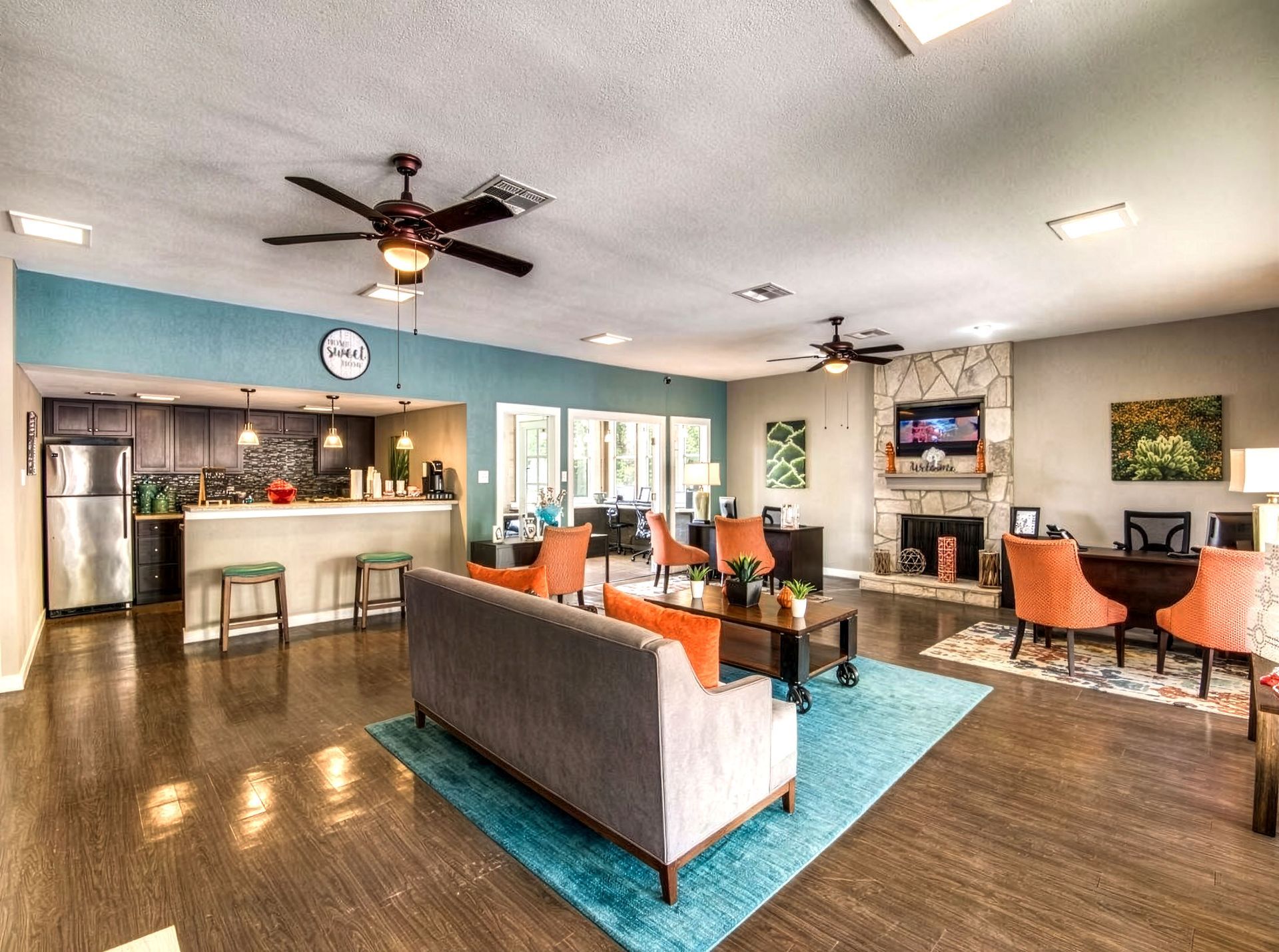 Modern living room with gray sofa, blue rug, fireplace, TV, and ceiling fans