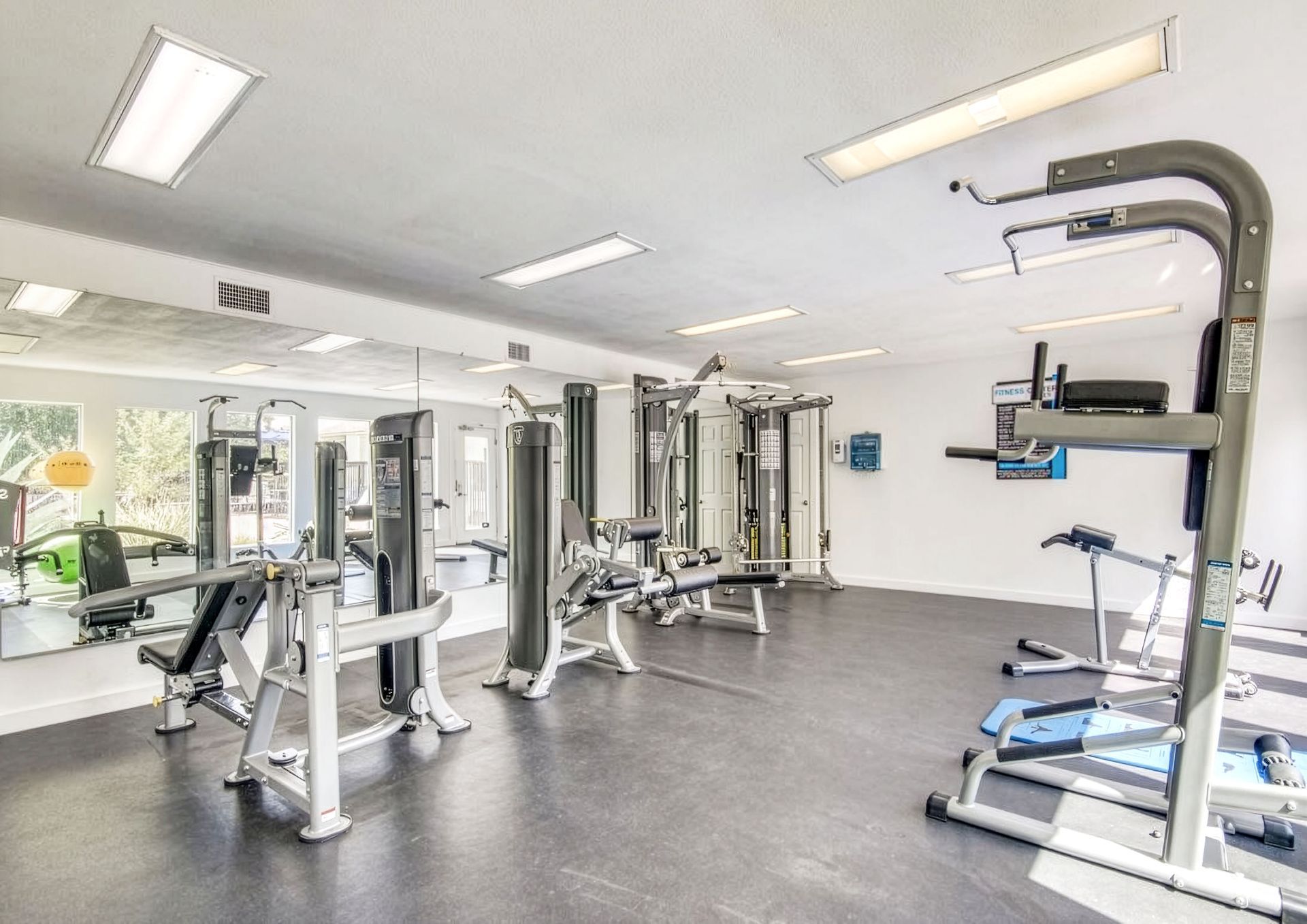 Modern gym interior with exercise machines, mirrors, and bright overhead lighting
