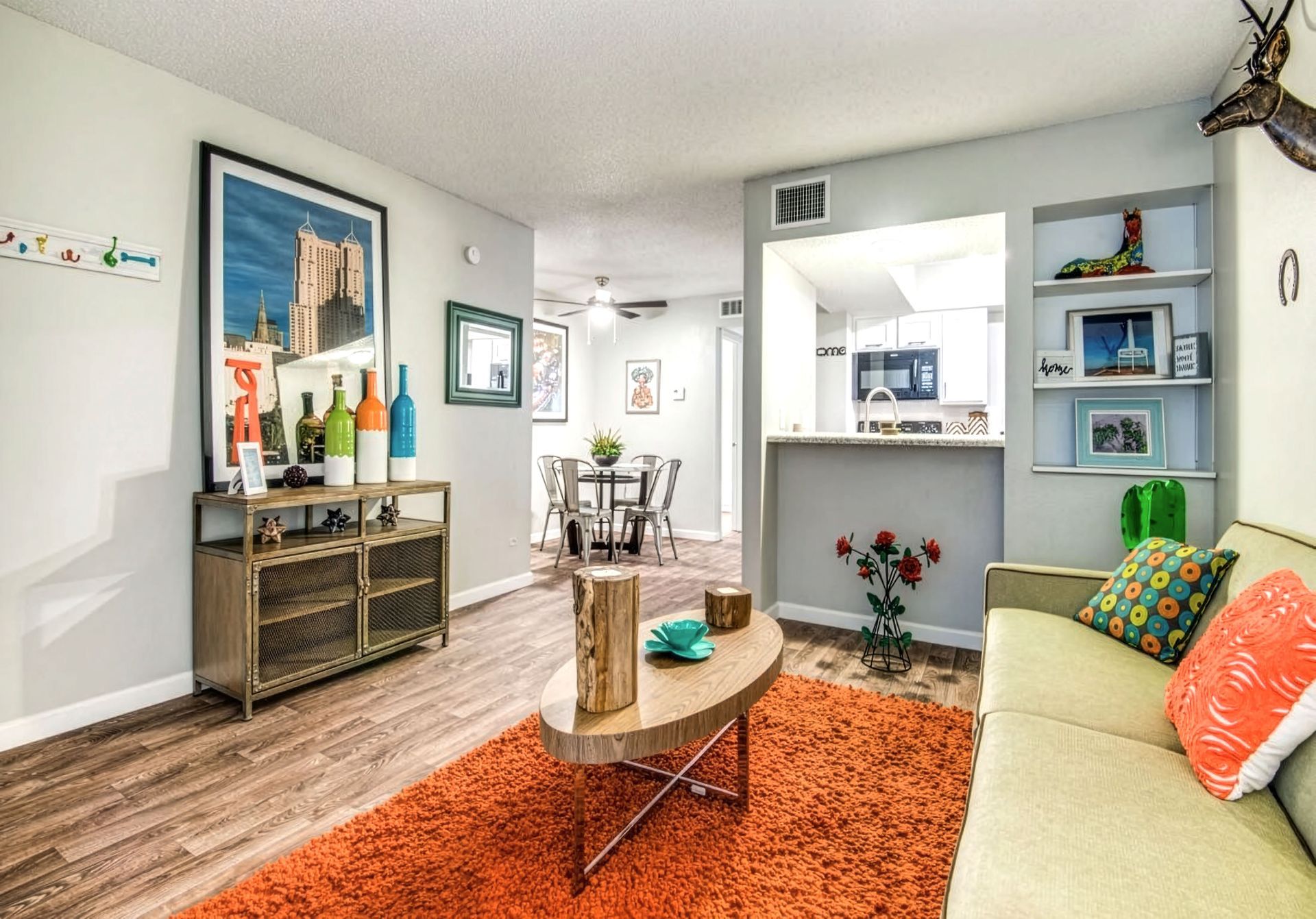 Bright living room with orange rug, beige sofa, coffee table, and colorful decor.
