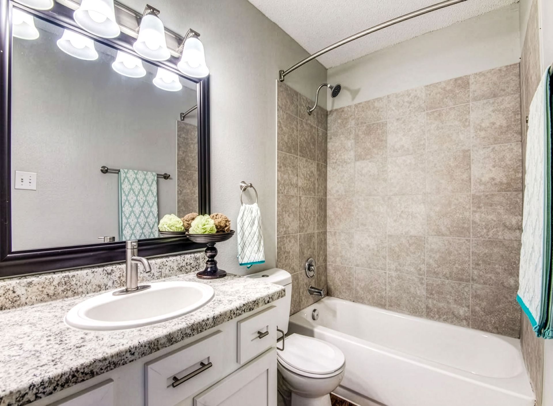 Modern bathroom with vanity, sink, mirror lights, tiled shower, and bathtub