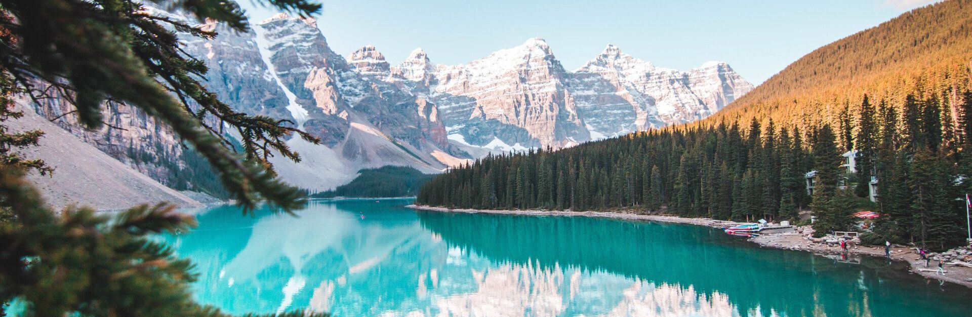 There is a lake in the middle of a forest with mountains in the background.
