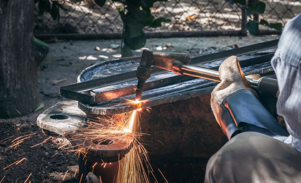 Person using an angle grinder to cut metal, with bright sparks flying outdoors.