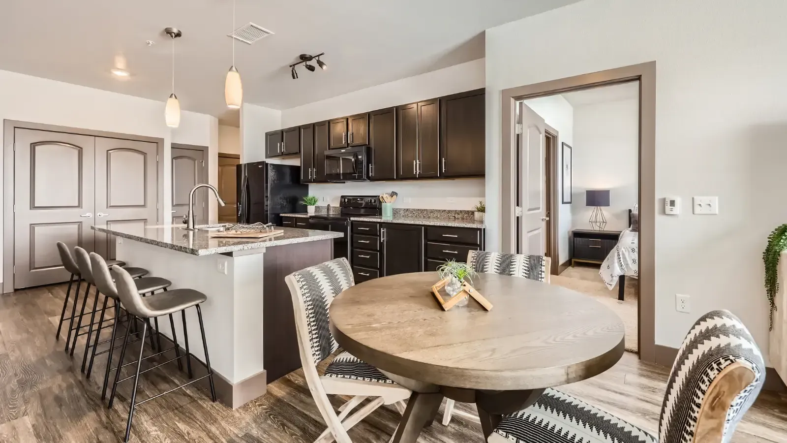Open-concept kitchen and dining area with dark cabinets, granite countertops, island, and round table.